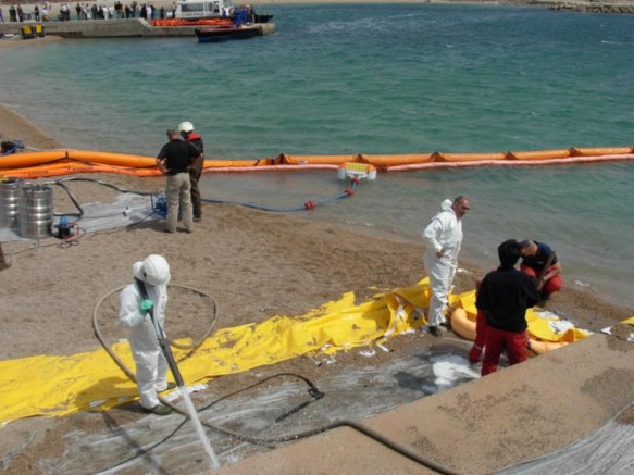 Barreras de contención desplegadas en el litoral y limpieza con trajes de protección